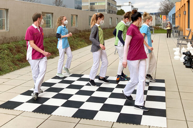 Mitarbeiter:innen tanzen auf einem Schachbrett am Boden. (Bild: FSW)